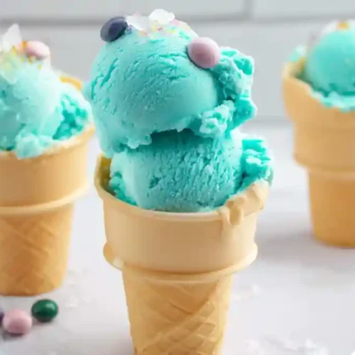 Blue bubble gum ice cream scoops in waffle cones with colorful gumballs and sprinkles