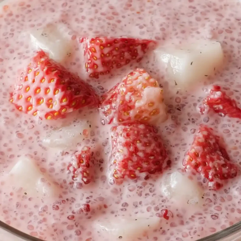 Close-up of strawberry sago with diced strawberries and coconut jelly in pink coconut milk base