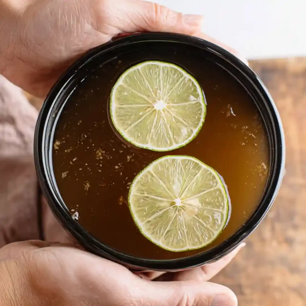 Fermented tejuino concentrate topped with lime slices in black jar