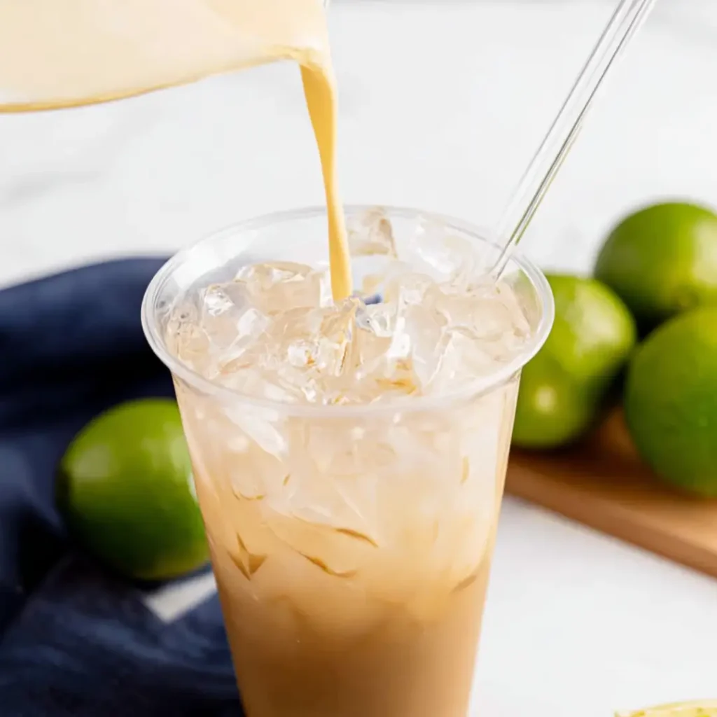 Stream of tejuino pouring into ice-filled cup