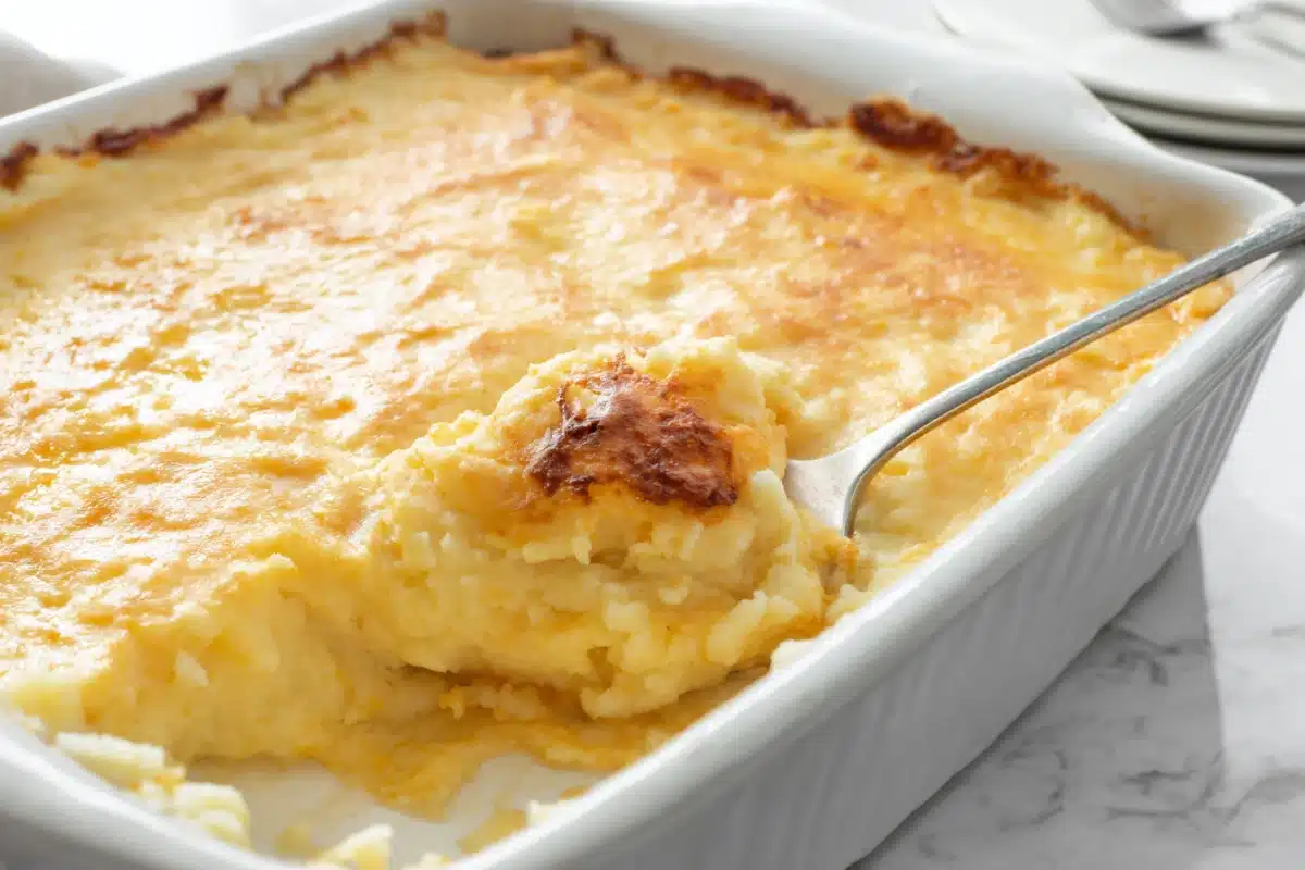 Creamy mashed potato casserole in a white baking dish with a golden top.