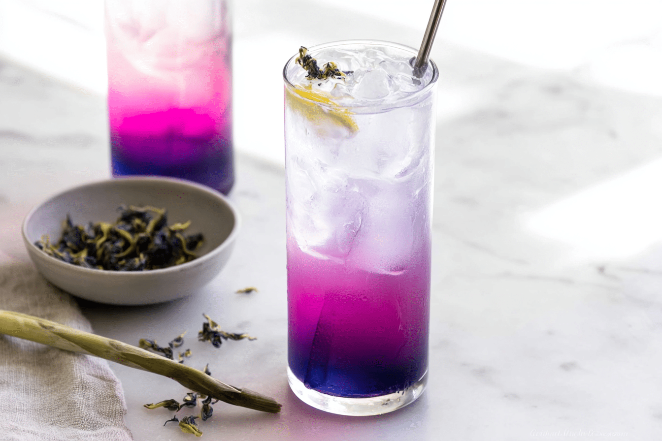 Vibrant butterfly pea lemonade in a tall glass, transitioning from blue to purple and yellow, garnished with fresh lemongrass and ginger slices for an herbal twist.