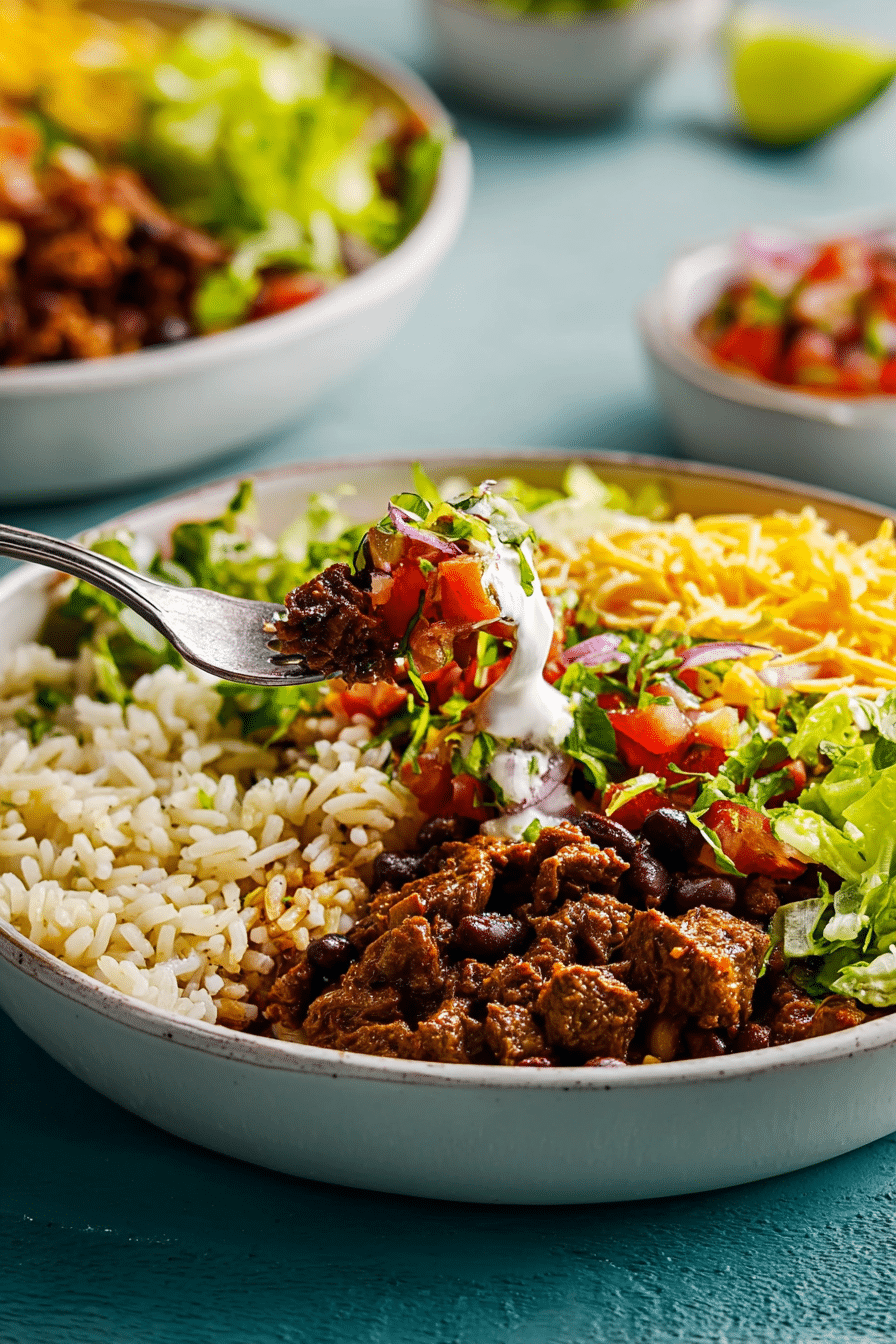 A close-up of a well-assembled burrito bowl showing layers of cilantro lime rice, black beans, and pico de gallo, ready to eat.