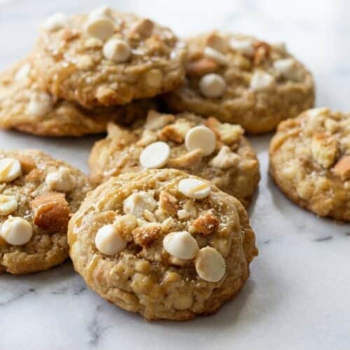 A plate of golden-brown banana pudding cookies with visible pieces of salted vanilla wafers and white chocolate chips.