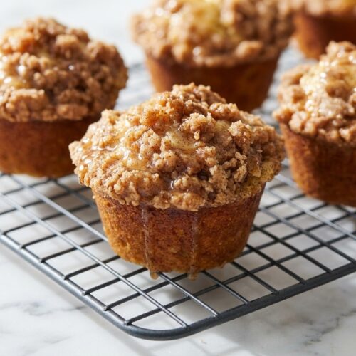 Close-up of golden Banana Streusel Muffins showcasing a rich brown butter and nutmeg-infused crumb topping.
