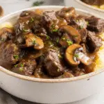 Platter of tender beef tips crock pot recipes, smothered in a deeply flavored brown gravy enhanced by balsamic and bloomed tomato paste, served over egg noodles.