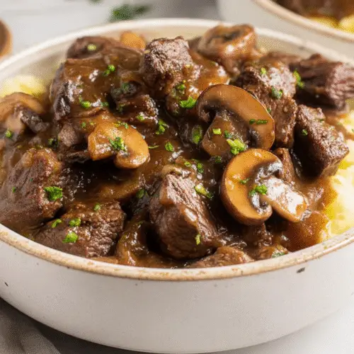 Platter of tender beef tips crock pot recipes, smothered in a deeply flavored brown gravy enhanced by balsamic and bloomed tomato paste, served over egg noodles.