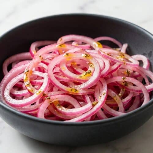 Vibrant pink cebolla curtida with red onion rings, green cilantro, and infused Aromatic Oil Bloom visible.