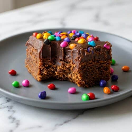 Plate of copycat cosmic brownies with shiny chocolate ganache and colorful candy sprinkles, made with brown butter andespresso powder for deep flavor.