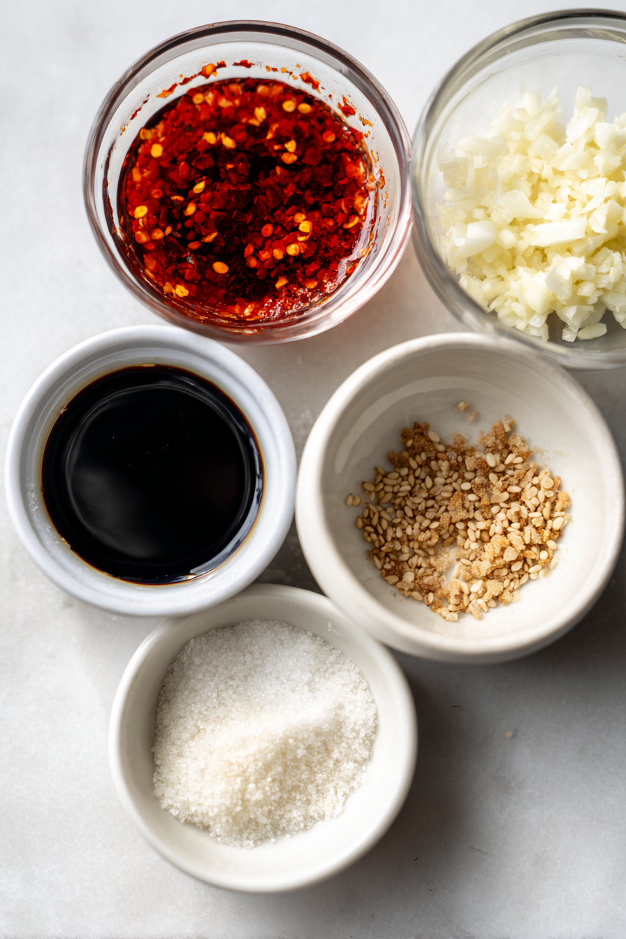 A flat lay of fresh ingredients for a flavorful dumpling sauce, including soy sauce, rice vinegar, grated ginger, and chopped scallions.