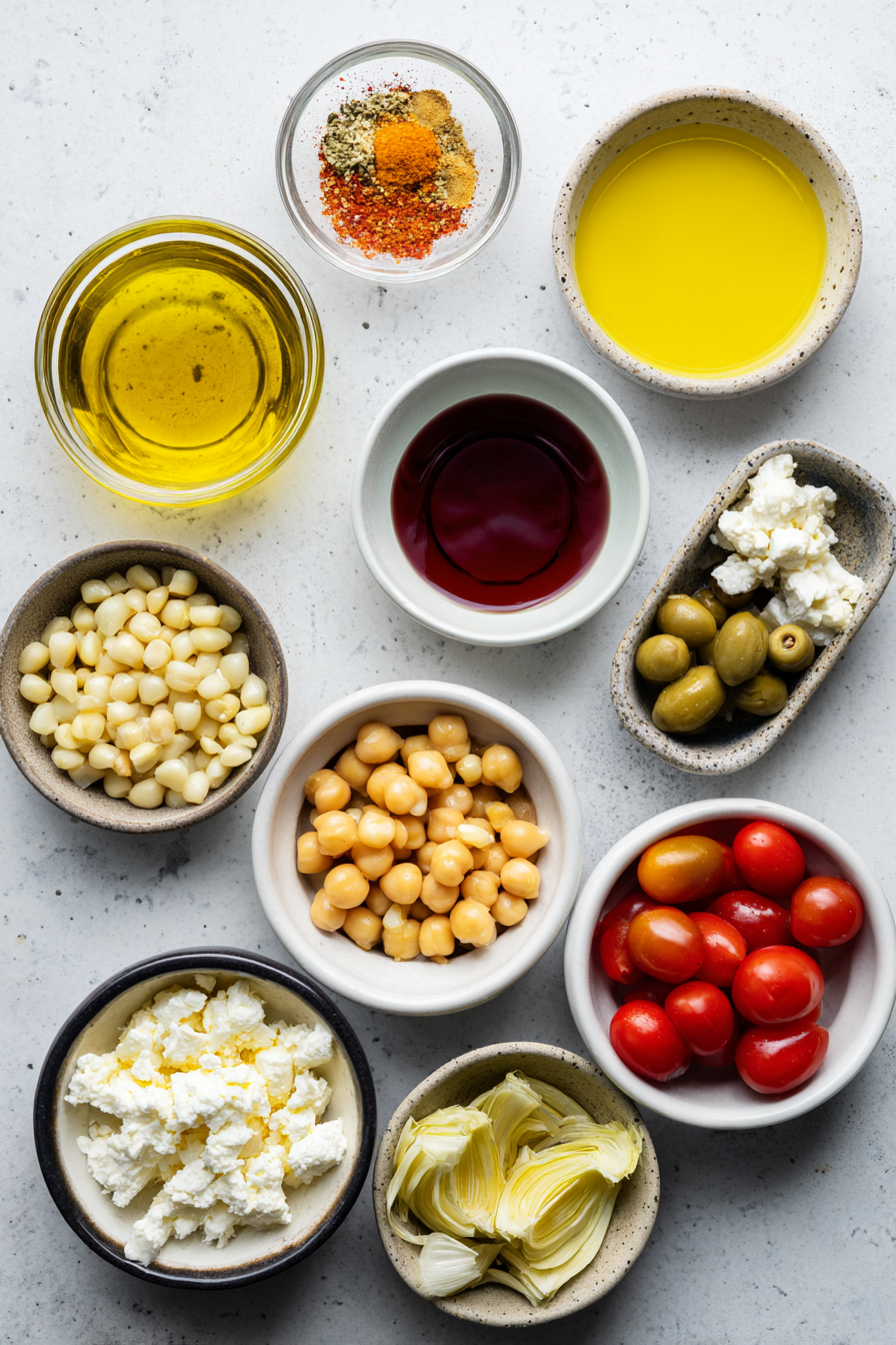 A flat lay of fresh ingredients for an iceberg lettuce salad with crispy chickpeas, including a head of lettuce, canned chickpeas, red onion, and seasoning spices.
