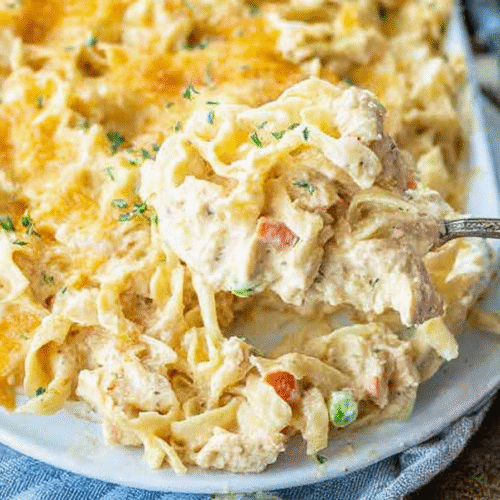 A bubbling chicken noodle casserole, golden-brown on top, showing a rich, creamy sauce infused with sautéed onion, celery, and thyme.