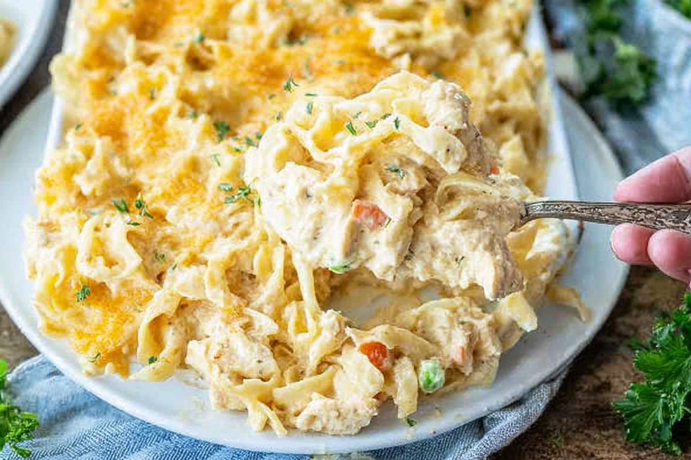 A bubbling chicken noodle casserole, golden-brown on top, showing a rich, creamy sauce infused with sautéed onion, celery, and thyme.