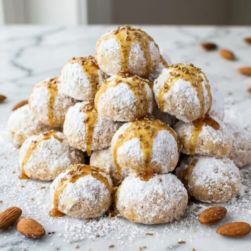 A platter of fluffy italian wedding cookies, each perfectly round and lightly dusted with confectioners' sugar highlighting the rich brown butter and toasted anisette notes.