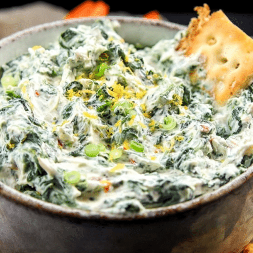 Creamy Knorr Spinach Dip served in a rustic bread bowl, garnished with fresh parsley and a bright lemon wedge, highlighting the fresh lemon zest.