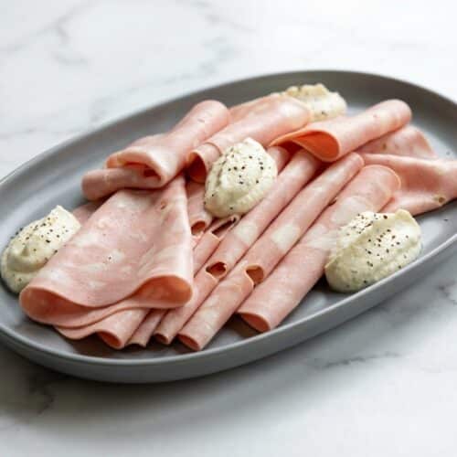 A gourmet mortadella sandwich on a toasted Kaiser roll, filled with fluffy whipped lemon-black pepper ricotta, thin-sliced mortadella, and a hint of Dijon.