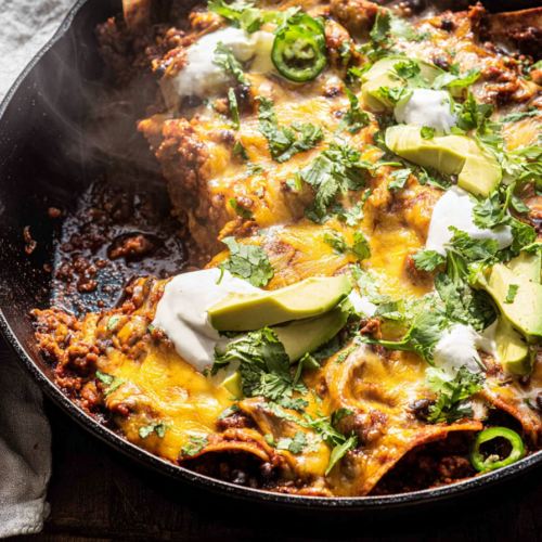 A vibrant one pan ground beef enchilada skillet, topped with melted cheese and fresh cilantro, showing the rich depth from bloomed spices.