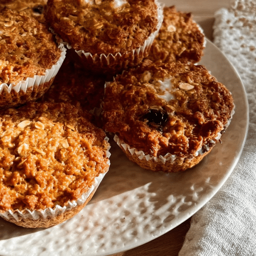 Close-up of golden brown protein breakfast muffins with oats and Greek yogurt, some with a slightly cracked top and visible oats.