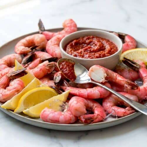 Platter of vibrant red jumbo shrimp cocktail served with a zesty horseradish sauce, showcasing the rich color from the Maillard-Shell Infusion.