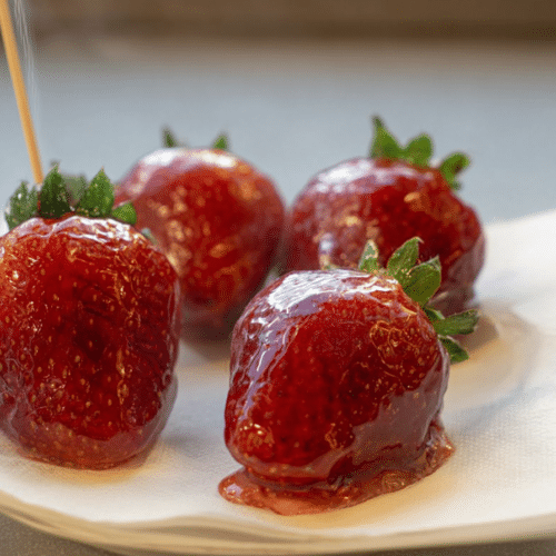 Shiny red strawberry tanghulu without corn syrup, featuring a perfectly clear, hard candy shell, with a hint of lemon adding to its glass-like finish.