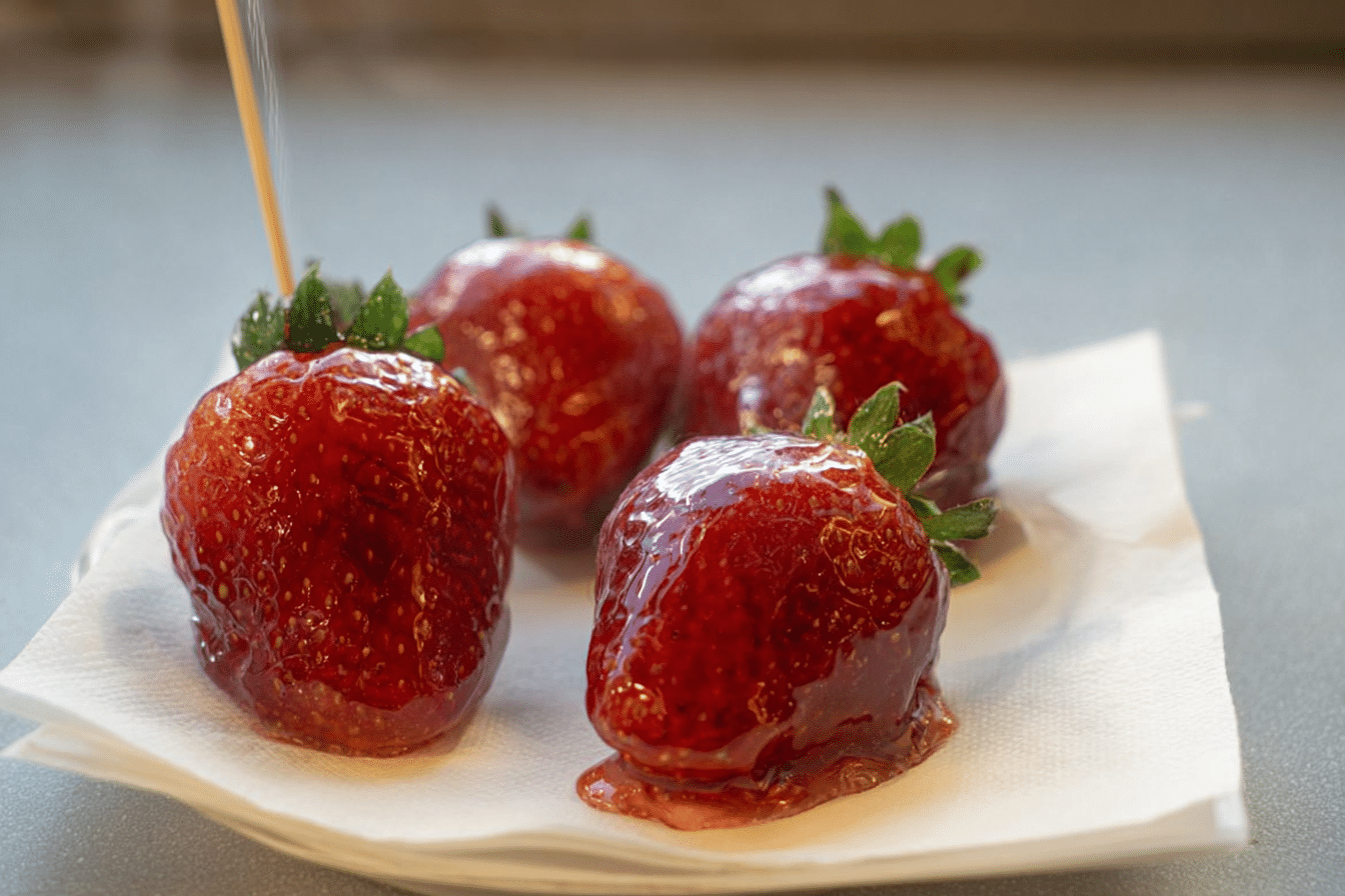 Shiny red strawberry tanghulu without corn syrup, featuring a perfectly clear, hard candy shell, with a hint of lemon adding to its glass-like finish.