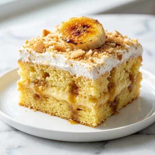 Banana pudding cake topped with rich brown butter whipped cream and caramelized brulée banana slices.