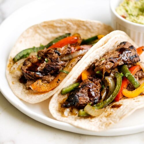 Sizzling Beef Steak Fajitas featuring a rich umami bomb marinade booster and charred peppers in a cast iron skillet.