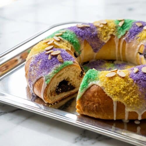 Traditional king cake recipe with a brown butter and almond infusion twist, topped with purple, green, and gold sugar.