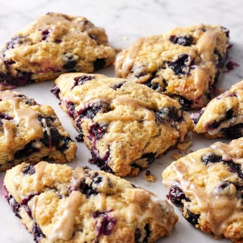Golden blueberry scones brushed with nutty brown butter and dusted with cane sugar on a wire rack.