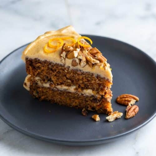 Spiced carrot cake recipe with velvety brown butter and orange zest cream cheese frosting on a serving plate.