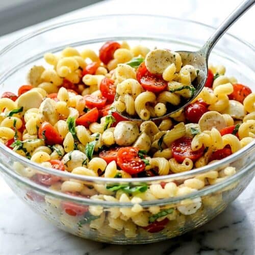 Caprese pasta salad featuring marinated ciliegine mozzarella and fresh basil chiffonade for deeper flavor.