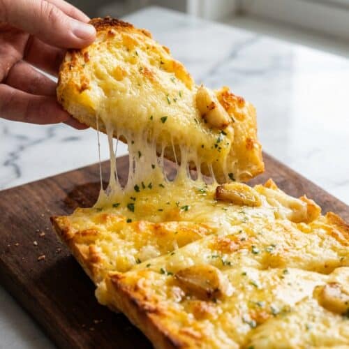 Slices of cheesy garlic bread recipe topped with molten mozzarella and rich double-garlic bone marrow butter.