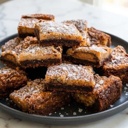 Slices of chocolate peanut butter ooey gooey cake with a salted espresso cocoa crust and flaky sea salt.
