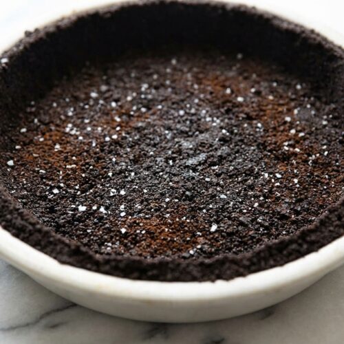 Dark oreo pie crust with sea salt and espresso powder pressed into a clear glass pie plate.