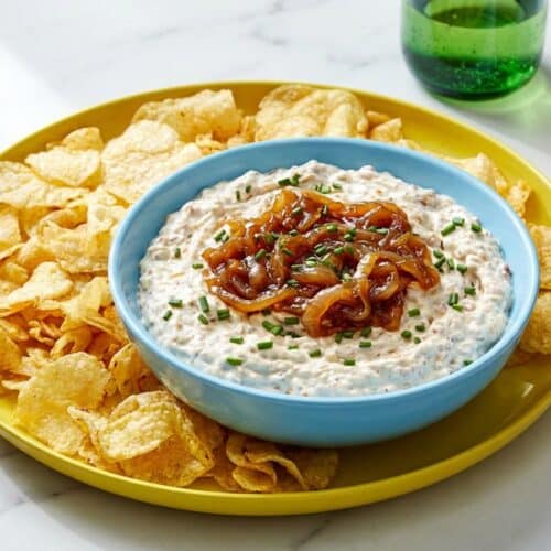 Creamy french onion dip in a white bowl, showing a deep golden hue from the sherry deglazing process.
