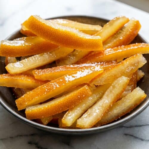 Translucent candied orange peel recipe strips with a glossy corn syrup and citric acid finish on a wire rack.