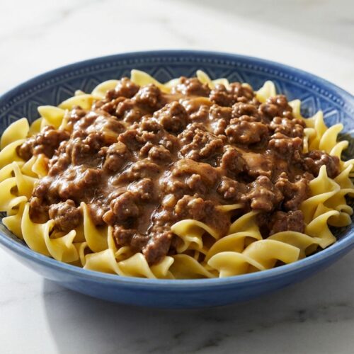 Creamy ground beef stroganoff over egg noodles, featuring an umami-rich sauce with tomato paste and Dijon mustard.
