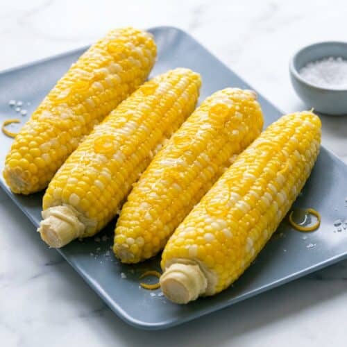 Citrus-honey poached sweet corn on a platter showing how to cook corn on the cob for a bright summer flavor.
