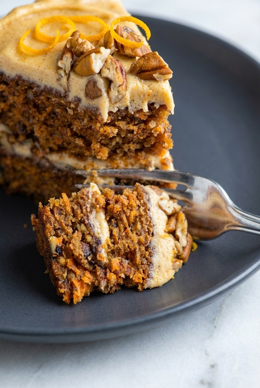 Close-up of a carrot cake recipe slice highlighting the tender, moist crumb and flecks of grated carrot.