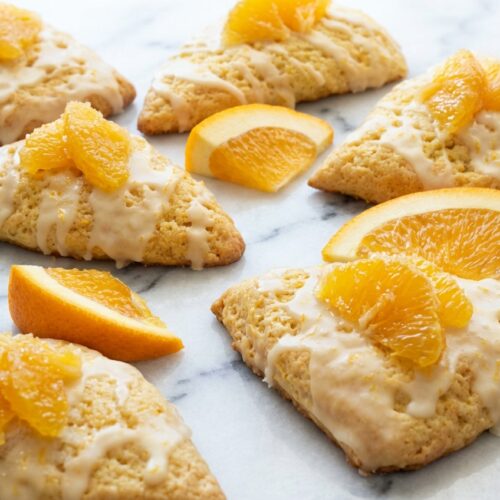 Glazed orange scones featuring a zesty citrus-sugar maceration for vibrant flavor and golden, tender edges.