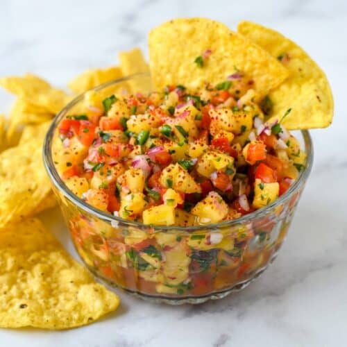 Pineapple salsa in a bowl dusted with red Tajín seasoning and drizzled with fresh passion fruit juice.