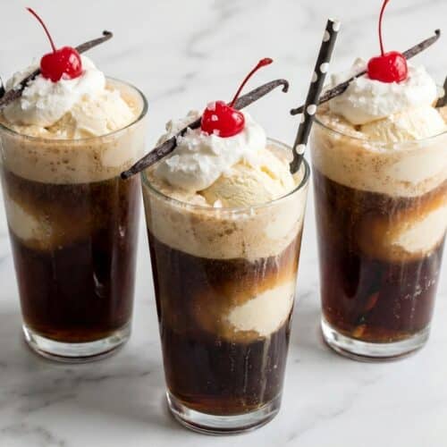 Salted vanilla coke floats in a frosted mug with whipped cream and a maraschino cherry topping.