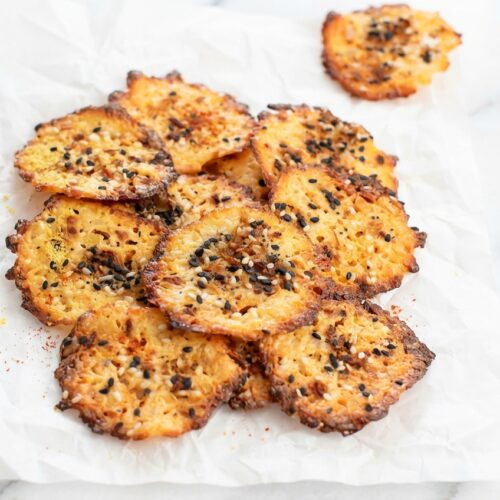 Crispy cottage cheese chips dusted with smoky paprika and savory nutritional yeast on a baking sheet.