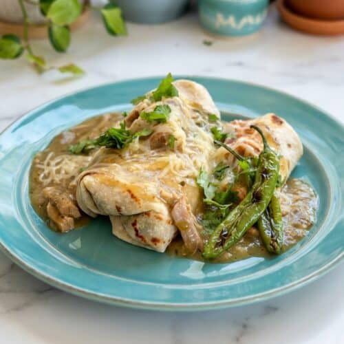 Smothered green chili burritos topped with cheese and flash-seared chiles for a smoky flavor profile.