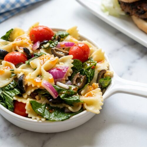 Farfalle spinach pasta salad tossed in a savory sun-dried tomato oil emulsion with feta and kalamata olives.