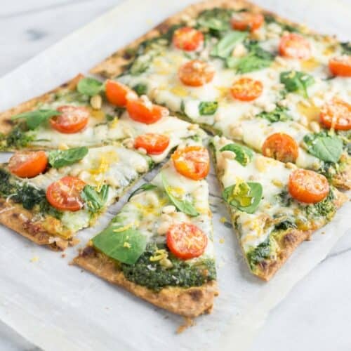 Spinach pesto pizza topped with fresh lemon zest and a drizzle of garlic-infused hot honey on a crispy crust.