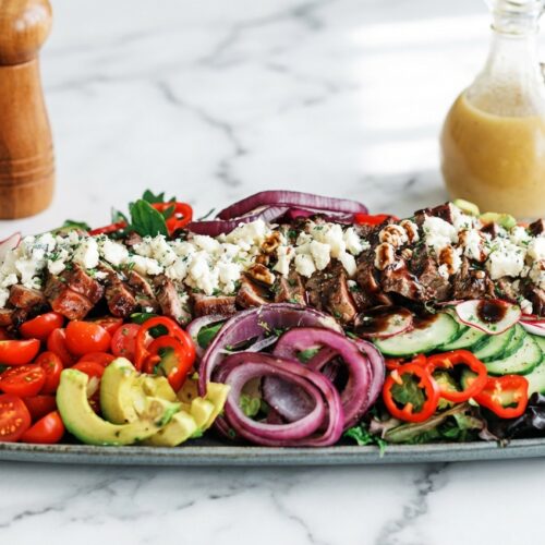 Sliced medium-rare steak salad over arugula with a rich umami-bomb balsamic glaze finish.