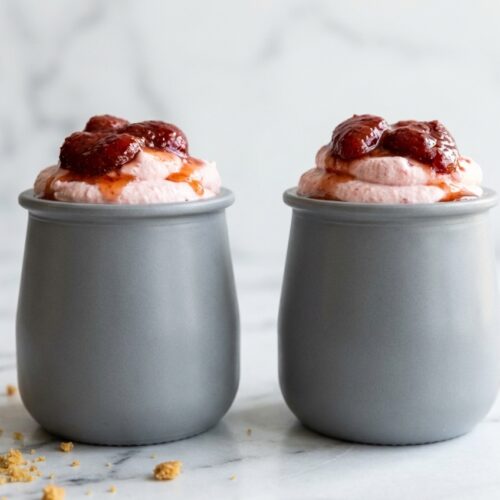 Fluffy strawberry cheesecake mousse topped with honey-roasted strawberry puree in a glass ramekin.