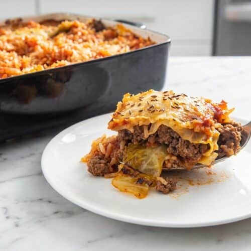 Bubbling stuffed cabbage roll casserole in a dish featuring a savory caraway crust and rich tomato sauce.