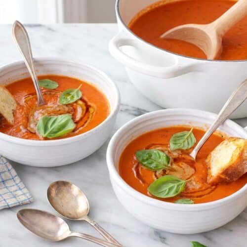 Creamy tomato basil soup in a white bowl with a swirl of nutty brown butter and smoked paprika oil.